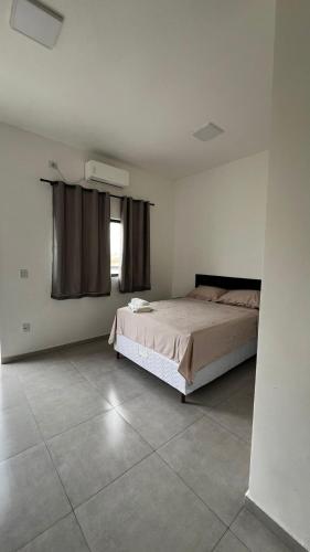 a bedroom with a large bed and a window at Alphaville Studios in Pirapora