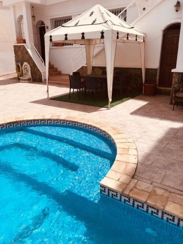a pool with a white umbrella and a table and chairs at Villa Oasis Ain El Turk in Aïn El Turk