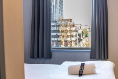 a bed with a pillow in front of a window at easyHotel Cardiff in Cardiff