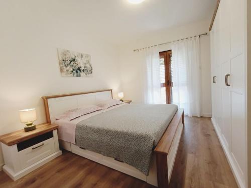 a white bedroom with a bed and a window at Apartment Vesna in Medulin