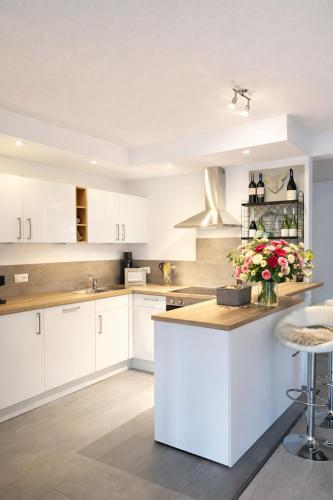 a kitchen with white cabinets and a vase of flowers on a counter at Romantik 2-6P in Mürlenbach