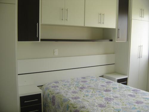 1 dormitorio con 1 cama y armarios blancos en Apartamento em Praia dos Ingleses, en Florianópolis