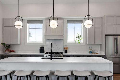 a kitchen with white cabinets and a white island with stools at 14BR Downtown Combo & Shared Seasonal Pool in New Orleans