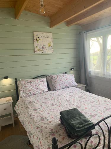 a bedroom with a bed with pink sheets and a window at Modern Cabin with large private garden in Old Romney