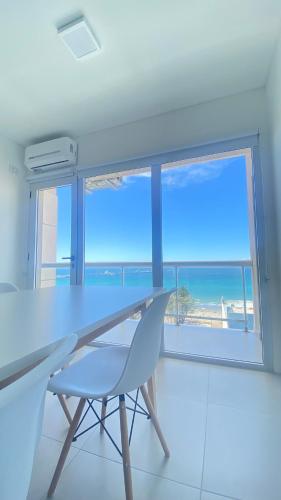 a table and a chair in a room with a view of the ocean at Bella Vista in Puerto Madryn