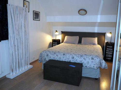 um quarto com uma cama com um edredão branco em Paris Côté Jardin em Chalifert