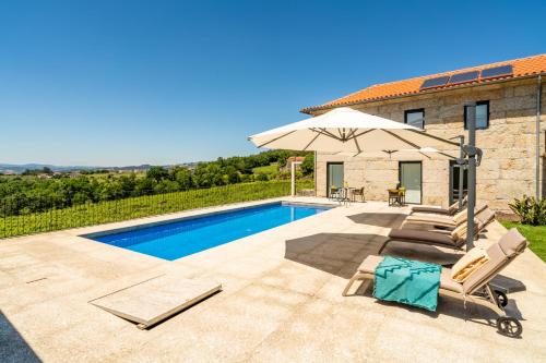 a villa with a swimming pool with chairs and an umbrella at Outeyro Retreat Country House in Marco de Canaveses