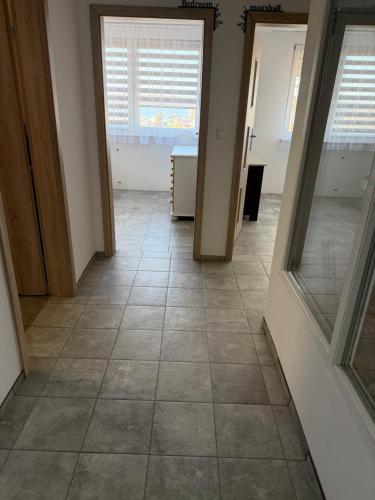 a hallway with a tile floor and two windows at Rodzinna Przystań Arkadia in Dominice