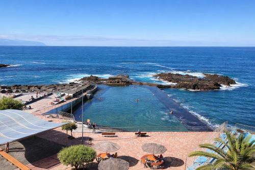 a beach with umbrellas and people in the water at Terraza con vistas al mar Tenerife Norte Mesa del Mar in Tacoronte