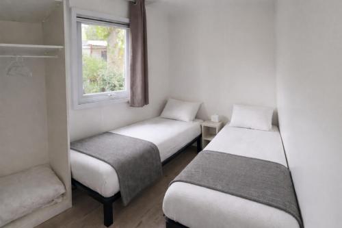 two twin beds in a room with a window at rouge gorge in Valras-Plage