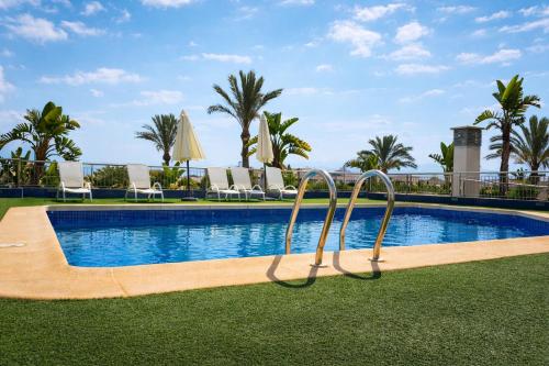 a resort pool with chairs and palm trees at La Loma in Águilas