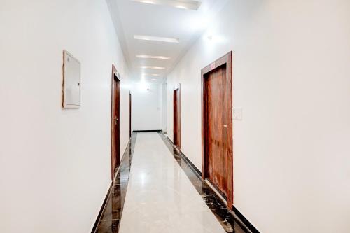 a corridor with wooden doors and white walls at HOTEL O SAMRAT INN in Prayagraj