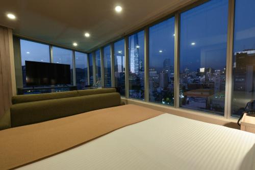 a bedroom with a couch and a large window at Hotel Terrado Lyon in Santiago