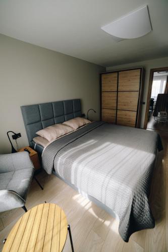 a bedroom with a large bed and a chair at MD Apartment in Rēzekne