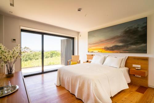 a bedroom with a white bed and a large window at Outeyro Retreat Country House in Marco de Canaveses