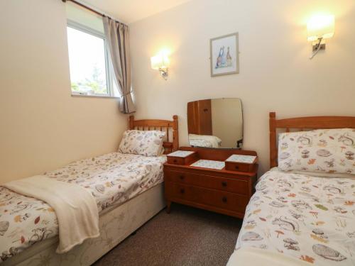 a bedroom with two beds and a mirror at Ford Coach House Cottage in Leek