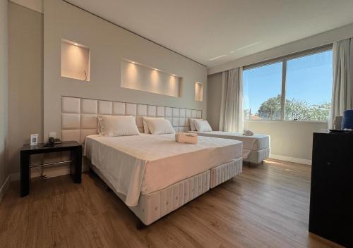 a bedroom with a large bed and a large window at Favorita Golden Hotel e Eventos in São José