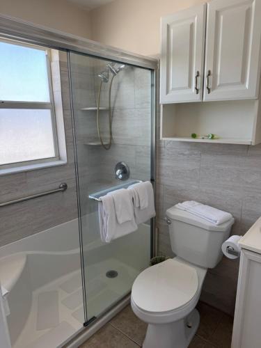 a bathroom with a toilet and a glass shower at Sierra Suites in Daytona Beach