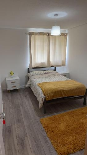 a bedroom with a bed with curtains and a rug at Two-bedroom house with a workspace in Basildon in Nevendon