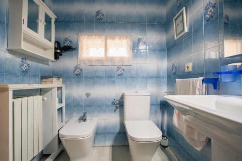 a blue tiled bathroom with a toilet and a sink at Acogedora casa histórica en Segovia by CABANA Rentals in La Lastrilla