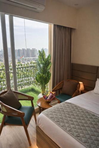 a hotel room with a bed and chairs and a window at The Rudraya - Suites in Greater Noida