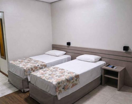 a room with two beds and a table at Hotel Dan Inn Uberlandia By Nacional Inn in Uberlândia