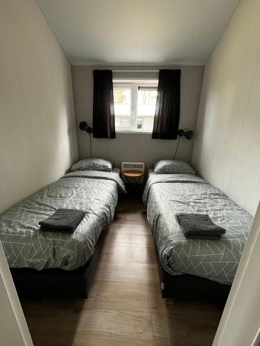 two beds in a small bedroom with a window at Veluwe Retreat Inn Otterlo! in Otterlo