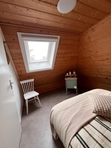 a bedroom with a bed and a window and a chair at It Jachtfjild in Het Jachtveld