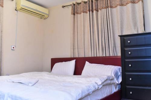 a bedroom with a bed and a dresser and a window at Skye Palace Apartment - Skye Regency 2 Bedroom Apartment in Akure