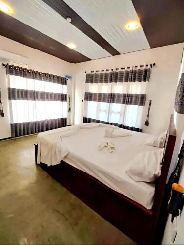 a bedroom with a large white bed with two windows at FA Resort in Panama
