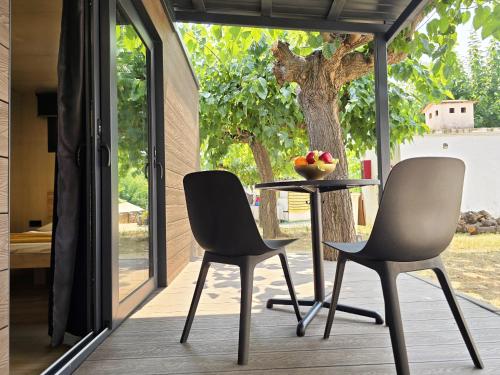two chairs and a table on a porch with a tree at Camping Costa Dorada Tiny Amaia in Canet de Mar