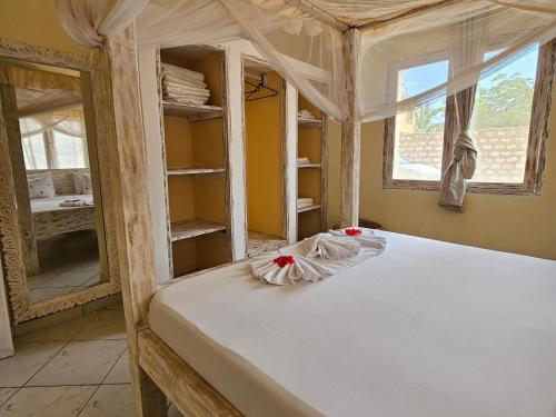 a bedroom with a canopy bed with a window at Orange apartment 1 in Watamu