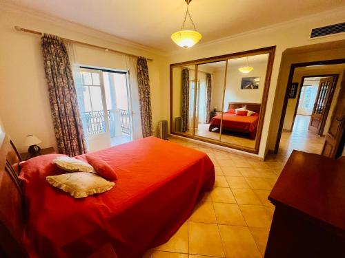 a bedroom with a red bed and a mirror at 2 bed appartment, close to the beach in Albufeira