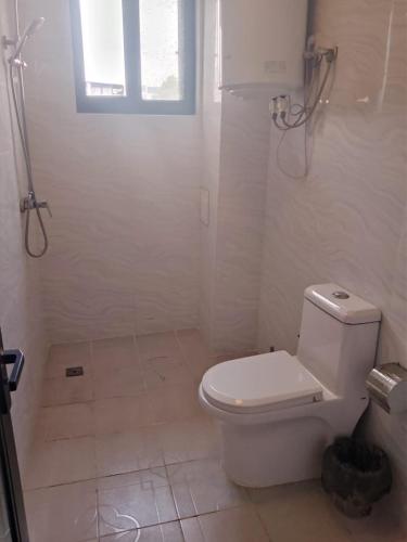 a white bathroom with a toilet and a window at 海客瀛洲 Haïke-Îlezone in Abidjan