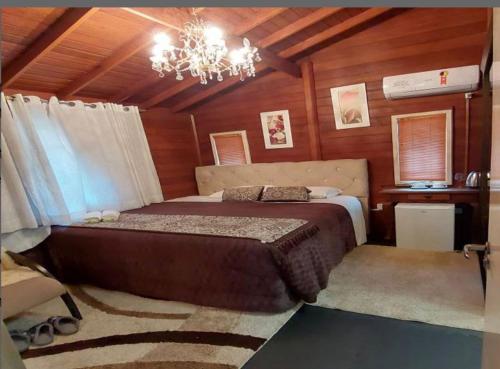 a bedroom with a large bed and a chandelier at Pousada requinte serrano in Urubici