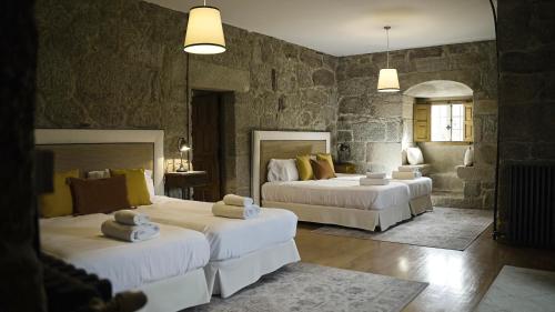 a bedroom with two beds and a stone wall at Pazo de San Pedro de Bembibre in Taboada