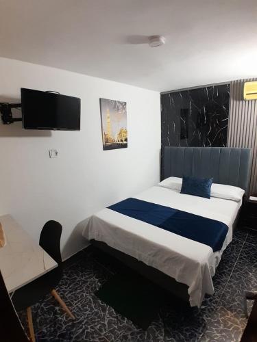 a bedroom with a bed and a desk and a tv at Bahia Suite Alojamiento Centro historico in Santa Marta