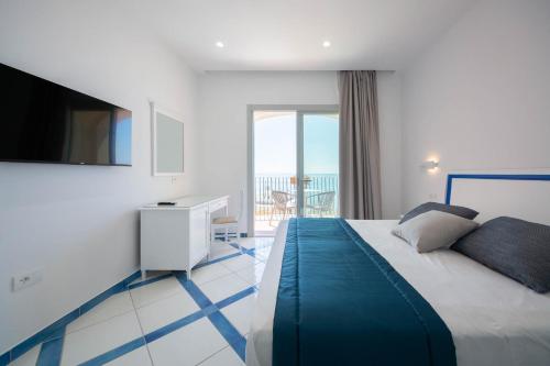 a bedroom with a bed with a television and a balcony at San Francesco Amalfi Coast Hotel in Maiori