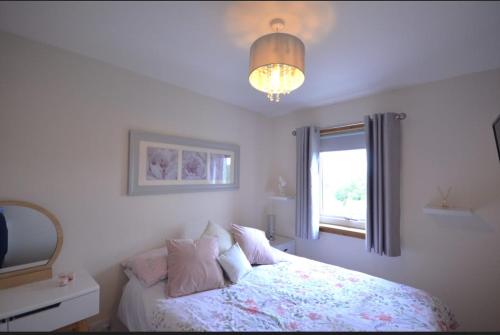 a bedroom with a bed and a window and a chandelier at Cozy 1 bed flat in Stornoway in Stornoway