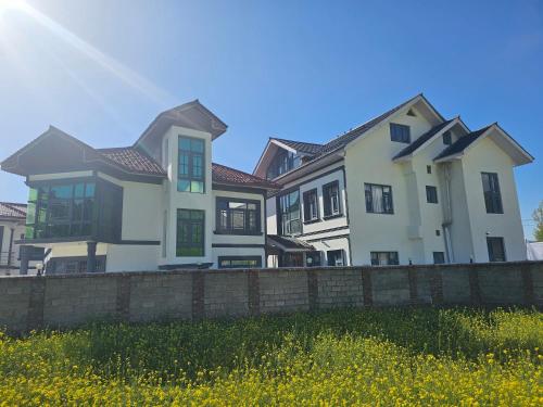 a large white house with a brick fence at Hotel Riverwood Kokernag in Wāngom