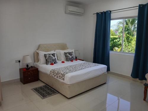 a bedroom with a bed with blue curtains and a window at Blue Sky Self Catering in Grand Anse