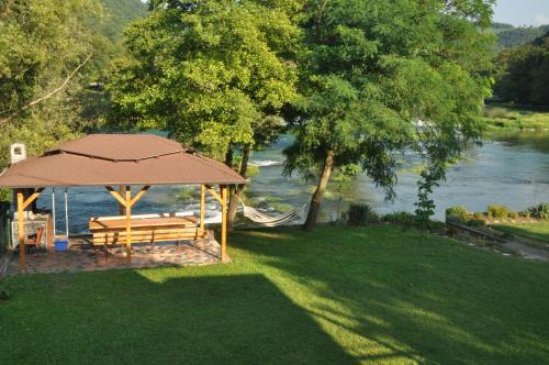 a picnic table with an umbrella next to a river at Kuća za odmor Komić in Smrdan