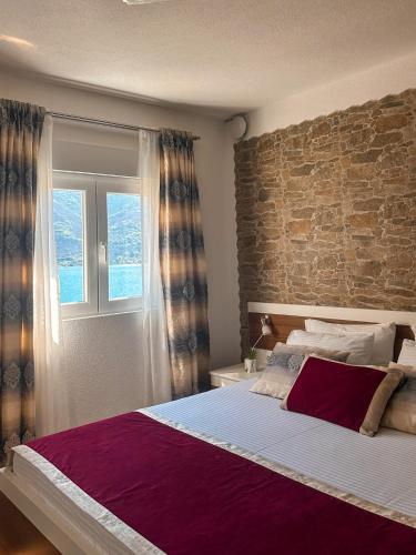 a bedroom with a large bed with a brick wall at Apartments Stella del Mare in Risan