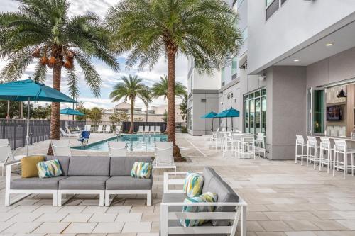 a patio with a couch and palm trees and a pool at TownePlace Suites by Marriott Orlando Near Universal in Orlando