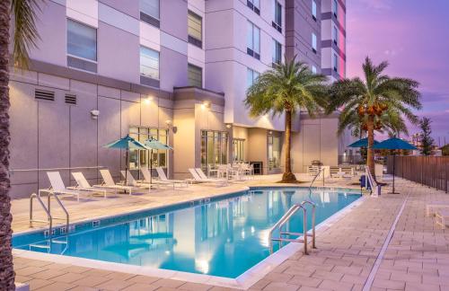 a pool with chairs and umbrellas next to a building at TownePlace Suites by Marriott Orlando Near Universal in Orlando