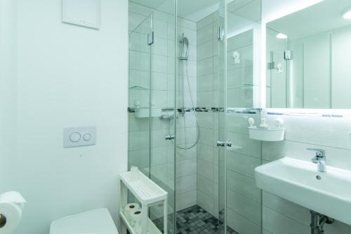 a white bathroom with a shower and a sink at Wirtshaus Feininger Hof in Benz