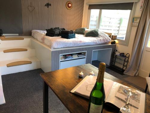a room with a bed and a table with a bottle of wine at The Zen Nest in Geel