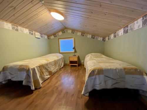 two beds in a room with green walls and wooden floors at VILLENKUJA 1 (3 mh ) in Tahkovuori