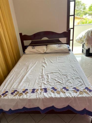 a bed with a white comforter with flowers on it at Brilho do Sol in Guarapari