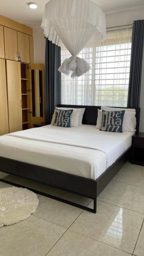 a large bed in a bedroom with a large window at Karibu comfort in Kisumu